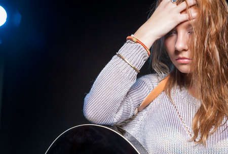 Music Concept and Ideas. Young Blond Female Posing with Guitar Against Black. Horizontal Image Orientationの写真素材