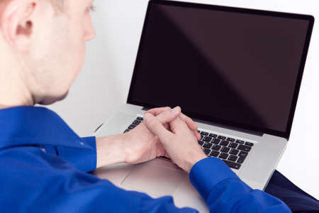 Backview of Caucasian Businessman With Folded Palms With Laptop Computer Indoors. Horizontal Imageの写真素材