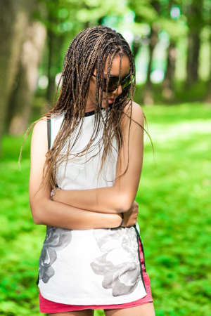African American Teenager Girl With Nice Dreadlocks Posing in Green Summer Forest Outdoors.Vertical...