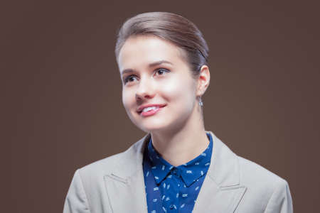 Natural Beauty portrait of Young Caucasian Girl in Pale Jacket and Blue Shirt Looking Forward.Against Brown Background. Horizontal Imageの写真素材