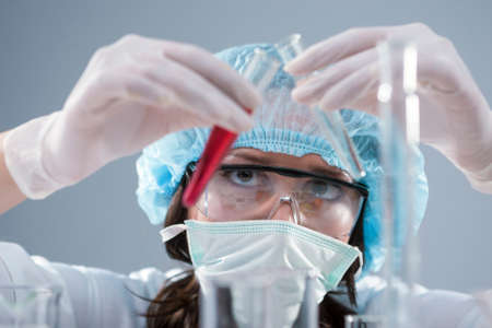 Closeup of Female Laboratory Staff Conducting Experiment with Two Luquid Specimens in Flasks In...