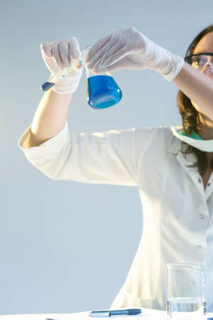 Medicine Concepts. Female Laboratory Assistant in Protective Gloves During Scientific Experiment With Liquid Components in Laboratory. Vertical Imageの写真素材