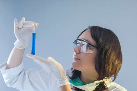 Female Laboratory Assistant Holding One Flask in Hand During Scientific Experiment. Horizontal Image...