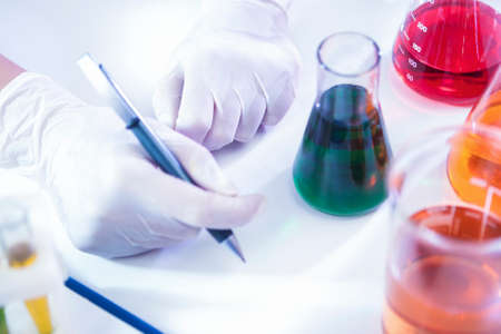 Closeup of hands of Female Laboratory Worker Dealing With Flasks Containing Liquid Chemicals. Horizontal Image Compositionの写真素材