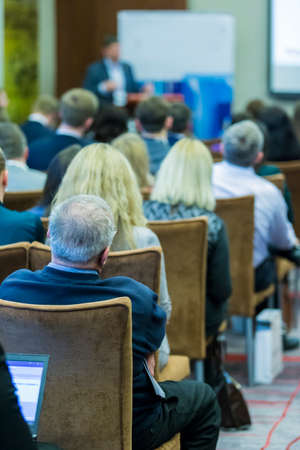 Business Concepts and Ideas. People at the Business Conference Listening to The Key Host Standing in Front of The Big Screen and Speaking.Vertical Imageの写真素材