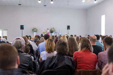 People Sitting In Lines During a Conference While Female Host Speaking on Stage. Horizontal Image Orientationの写真素材