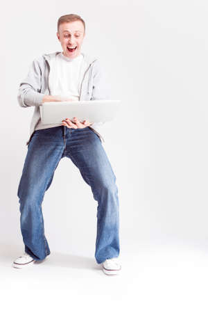 Youth Lifestyle Concepts and Ideas. Full Length Portrait of Happy Caucasian Man in Casual Clothing Posing with Laptop on Hands Against White Background. Vertical Shotの写真素材