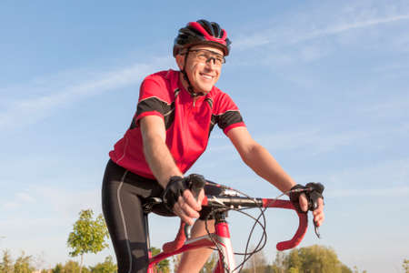 Cycling Concepts. Smiling Professional Road Cyclist During Ride on Bike Outdoors. Completely Equipped in Professional Outfit.Horizontal Imageの写真素材