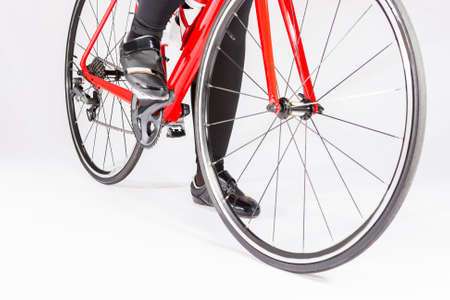 Cycling Concepts. Closeup of Legs of Female Cyclist and Wheels of the Road Bike Placed in Studio....