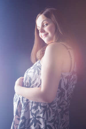 Family Ideas and Concepts. Happy smiling Caucasian Brunette Pregnant Woman Posing Against Black. Vertical Image Compositionの写真素材