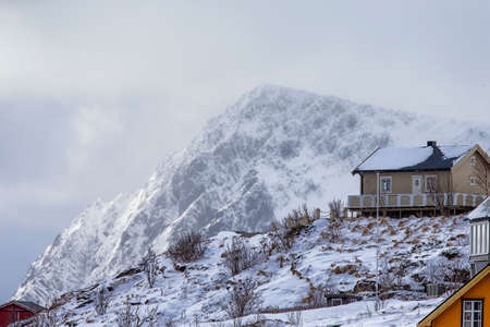 Traditional Norwegian Wooden House in Lofoten Islands Mountain Slope Against Cloudy Sky and Mountain.Horizontal Image Compositionの写真素材