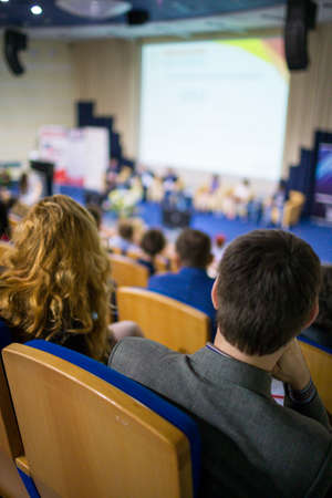 Business and Entrepreneurship Ideas. Female Speaker On Stage Giving a Talk at Business Meeting or Conference. Back View of the Listeners.Vertical Shotの写真素材