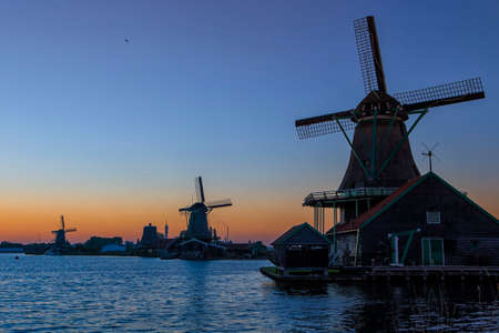Travel Ideas and Concepts. Amazing Picturesque View of traditional Dutch Windmills At Sunset During Golden Hour in Zaanse Schans near Amsterdam. Horizontal Image Compositionの写真素材