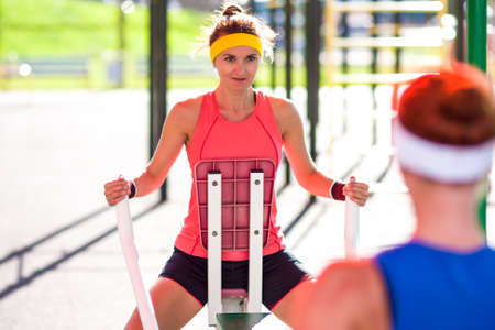 Sport Ideas and Concepts.Two Sexy Caucasian Female Athletes in Professional Outfit Having a Rowing Exercises for Arms Muscles.Horizontal Imageの写真素材
