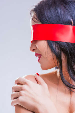 Caucasian Brunette Woman Posing with Red Ribbon Blinder on Eyes with Passionate Sensual Expression.の写真素材