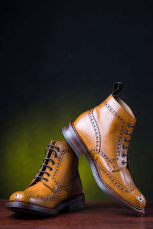 Footwear and Shoes Concepts. Pair of  Premium Tanned Brogue Derby Boots Shoot Against Dark Background.Vertical Imageの写真素材