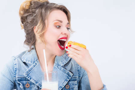 Food Ideas and Concepts. Young Caucasian Blond Girl Having Fun with Cup of MIlk and Donut...