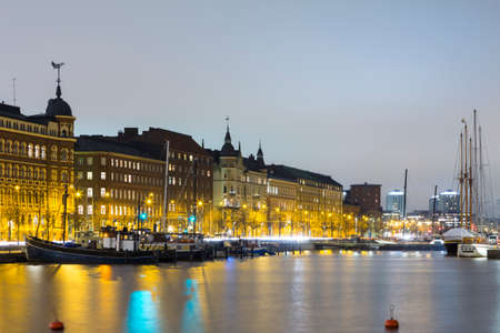 Travel Destinations. Line of Traditional Finnish Houses in Helsinki in Front of Waterline of Old Quay, Shot During Blue Hour. Horizontal Imageのeditorial素材