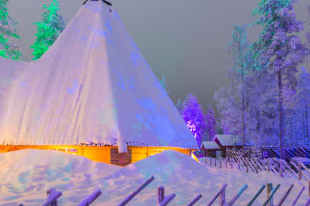 Travel Concepts and Ideas. Marvelous Lapland Houses in Suomi Village in Front of Marvelous Highlighted Winter Forest Scenery.Horizontal Shotの写真素材