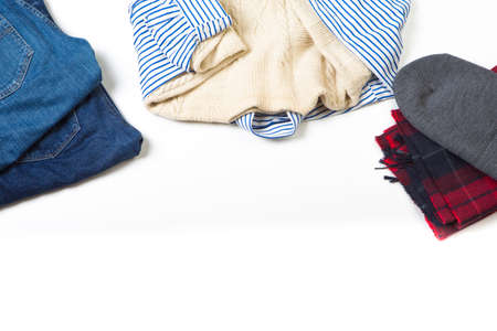 Fashion Ideas and Concepts. Man's red Checkered Scarf with Gray Hat,Heap of Blue Jeans and Striped Shirt with Woolen White Pullover Over White Background. Copyspace.Horizontal Image Compositionの写真素材