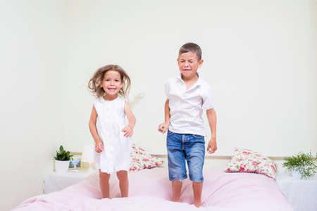 Family Values and Relationships. Happy and Excited Kids Playing Indoors. Jumping On The bed Together.Horizontal Image Orientationの写真素材