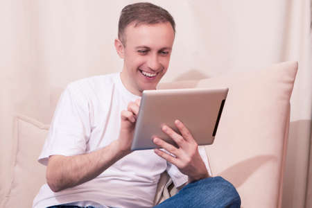 Technology Concepts. Happy Caucasian Man with Tablet Computer Chatting on Couch. Posing  in Home...