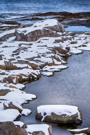 Travel Ideas and Concepts. Snowy and Stony Lofoten Islands Seascape in Norway Separately Covered with Snow.Vertical Image Orientationの写真素材