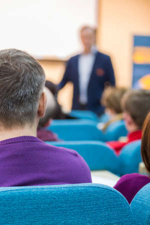 Male Presenter Speaking in Front of a Big Screen for The Group Of Listeneres During a Conference. Vertical Imageの写真素材