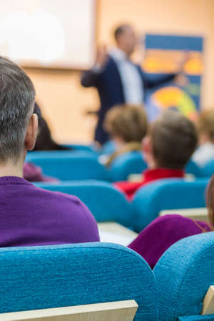 Expressive Male Presenter Speaking in Front of a Big Screen for The Group Of Listeneres During a Conference. Vertical Orientationの写真素材