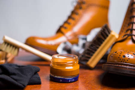Footwear Concepts and Ideas. Extreme Closeup of Premium Male Brogue Tanned Boots with Lots of Cleaning Accessories on Foreground.Horizontal Image Orientationの写真素材