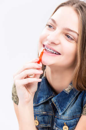 Dental Health Ideas and Concepts.Smiling Caucasian Female Teenager With Teeth Braces. Cleaning Brackets Using Bristle Brush. Vertical Composiionの写真素材