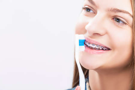 Dental Health Concepts. Closeup Portrait of Blond Caucasian Teenage Girl Wearing Teeth Braces. Brushing Her Teeth with Manual Brush.Horizontal Image Compositionの写真素材