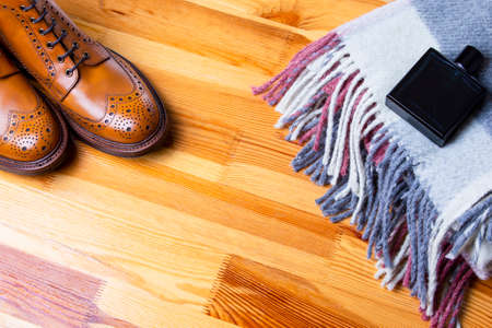 Composition Made Up Of Mans Brooge Boots in Tan, Wool Scarf and Perfume Bottle On Wooden Yellowish Background.Horizontal Imageの写真素材