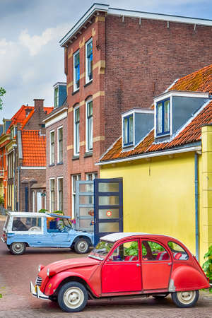 Travelling Through the Europe. Two Old Fashioned Retro Cars in Small Dutch City Outdoor. Vertical Imageのeditorial素材