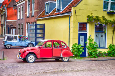 Travelling Through the Europe. Two Old Fashioned Retro Cars in Small Dutch City Outdoor. Horizontal Imageのeditorial素材