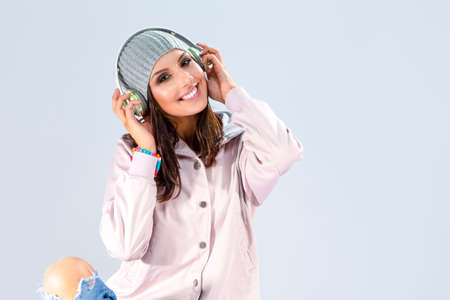 Music Concepts. Positive Happy Caucasian Brunette Girl in Pink Hoodie Listening to Music in...