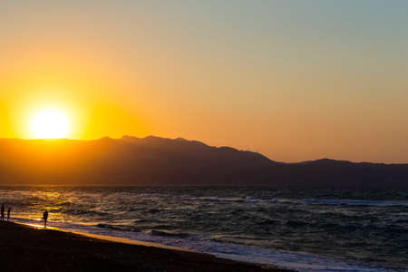 Amazing Picturesque Sunset on Heraklion Beach on Crete Island in Greece. Silhouettes Of People Wakling Along The Seashore. Horizontal Image Orientationの写真素材