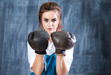 Female Boxer Posing in Brown Leather Boxer Gloves Against Blackboard. Hands Lifted in Front....