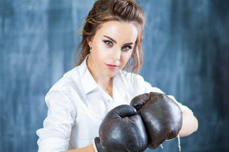 Portrait of Cute Smiling Caucasian Female Boxer Posing in Brown Leather Boxer Gloves Against Blackboard. Horizontal Image Compositionの写真素材