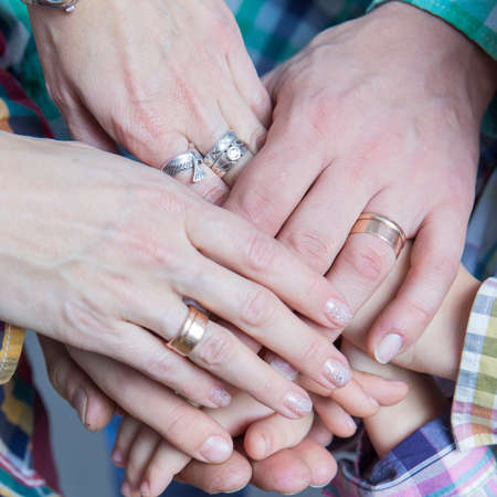 Closeup View of Young Caucasian People Connecting Their Hands Together. Stack of Five Pairs of Hands Demonstrating Unity, Teamwork and Friendshipの写真素材
