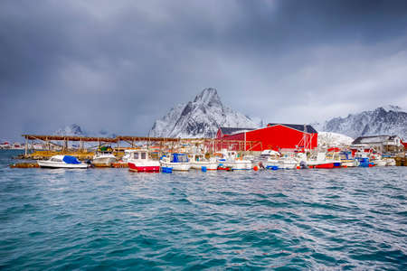 Travel Ideas. Red Fisherman Houses and Line of Fisherman Boats at Pier on Lofoten islands at a Spring Sunny Day.Horizontal image Orientationの写真素材