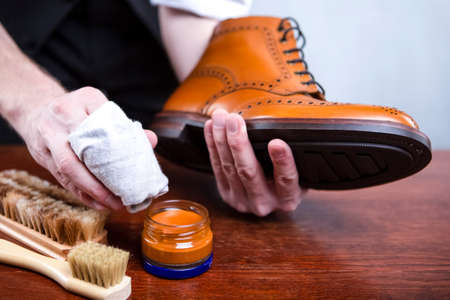 Close Up of Mans Hands Cleaning Luxury Calf Leather Brogues with Special Cloth. Horizontal image...