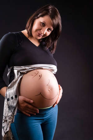 Pregnant Caucasian Woman Smiling Abdomen Against Black Background. Vertical image Compositionの写真素材