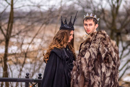 Art Photography and Cosplay.Caucasian Couple as King and Queen in Fur Medieval Outfit With Crowns Posing Together Outdoors.Horizontal Shotの写真素材