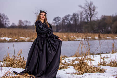 Mysterious Lady With Long Hair in Black Raincoat Posing In Forest outdoors.Horizontal image...