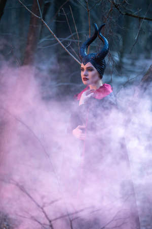 Costume Drama. Mysterious Female Posing in Black Raincoat in Early Spring Forest. Horizontal Image Orientationの写真素材