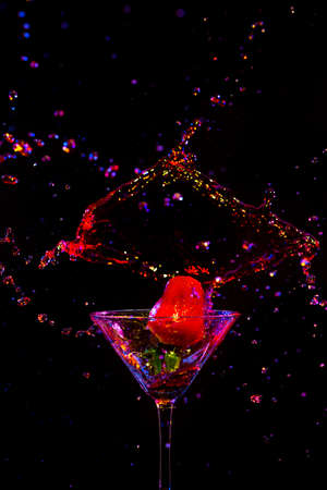 Strawberry Falling to Whineglass with Colorful Liquid. Over Black Background. Vertical Imageの写真素材