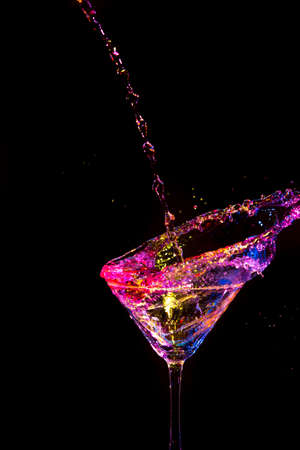 Splash Photography. Droplets Along With Burst of Colorful Liquid in Wine Glass. Isolated Over Black. Vertical Image compositionの写真素材