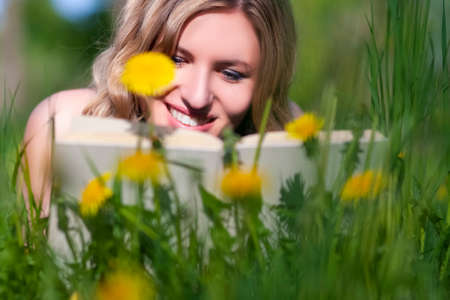 Closeup Portrait of Happy Caucasian Female With Book Reading Outdoors on Lawn. Horizontal Shotの写真素材