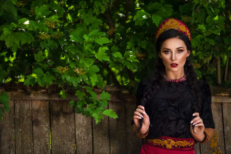 Glamour Fashion Model in Russian Style Decorated Kokoshnik Posing Outdoors Against Old Wooden...